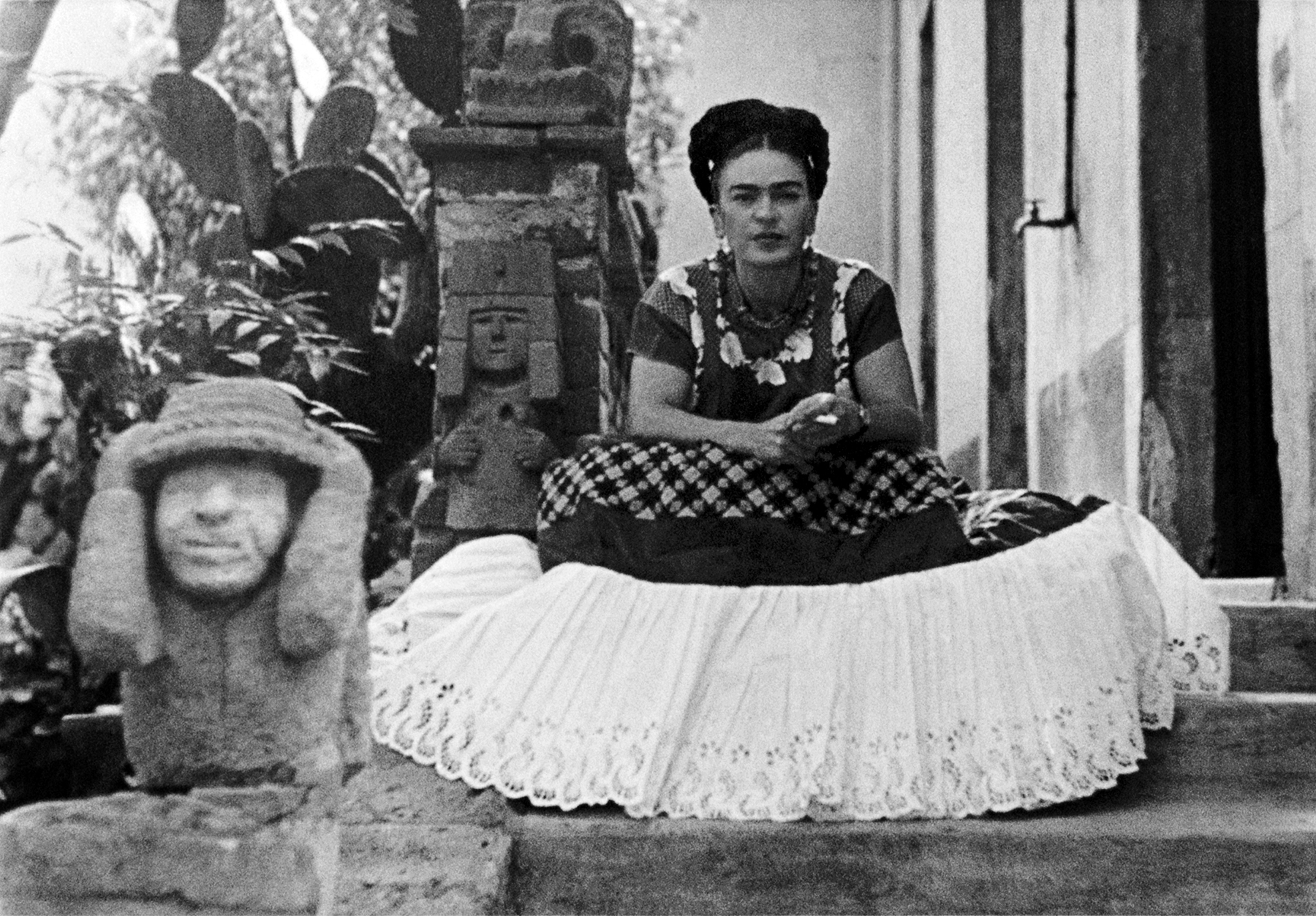 Photo of Frida sitting next to sculpture by Mardonio Magana